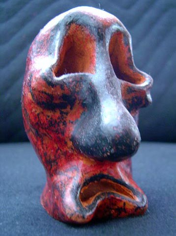 Escultura de cerâmica com a face da dor, pintada a giz de cera e envernizada.