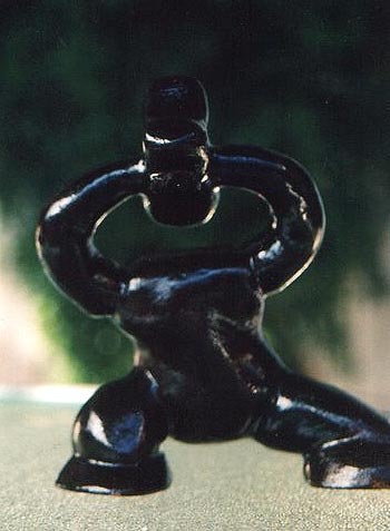 Escultura de um ser, sem pescoço, segurança sua cabeça já quase perdida, fora do corpo, a ponto de perdê-la.